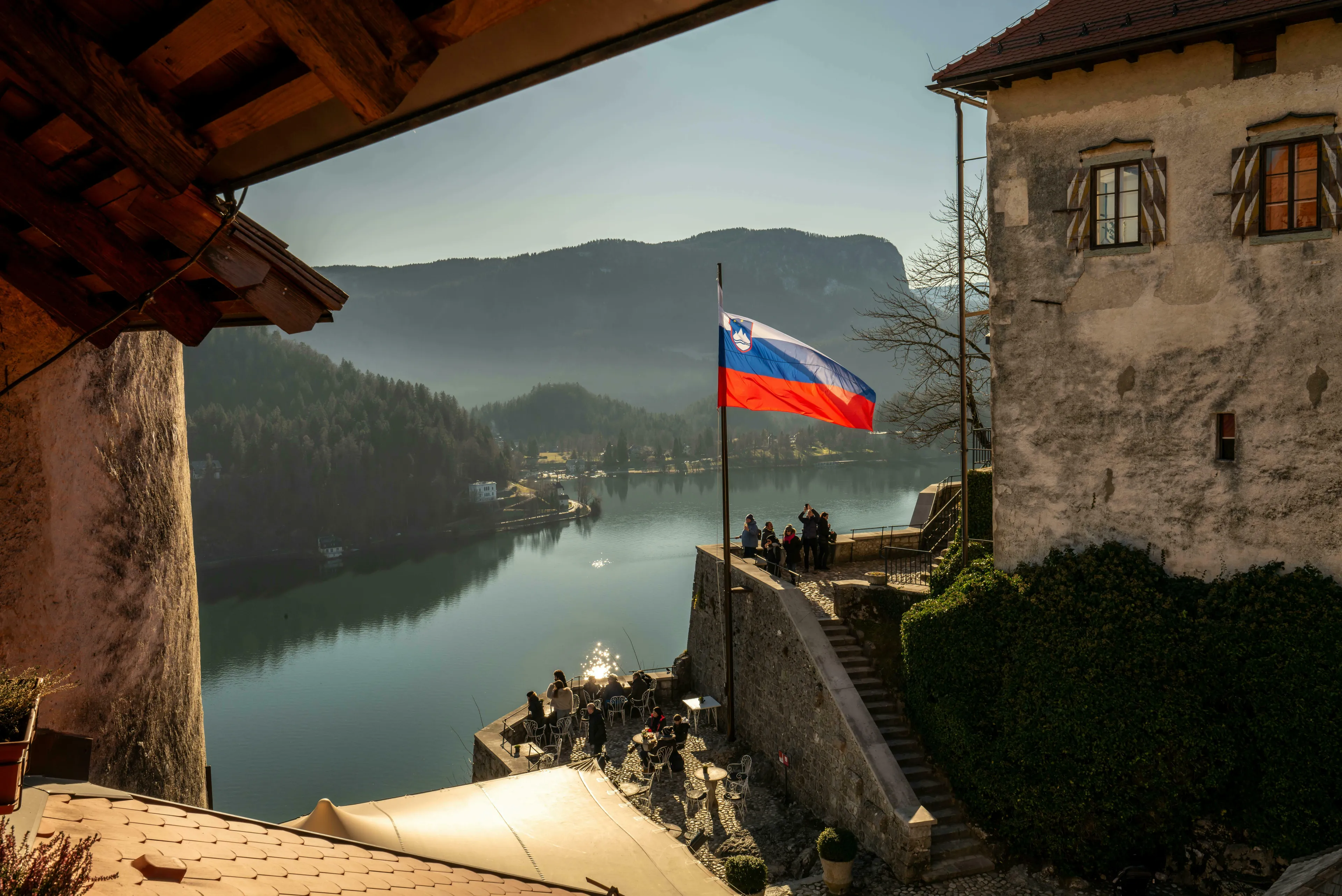 Slovenian flag flying over Lake Bled, Slovenia, with a medieval building in the foreground. Europe questions.