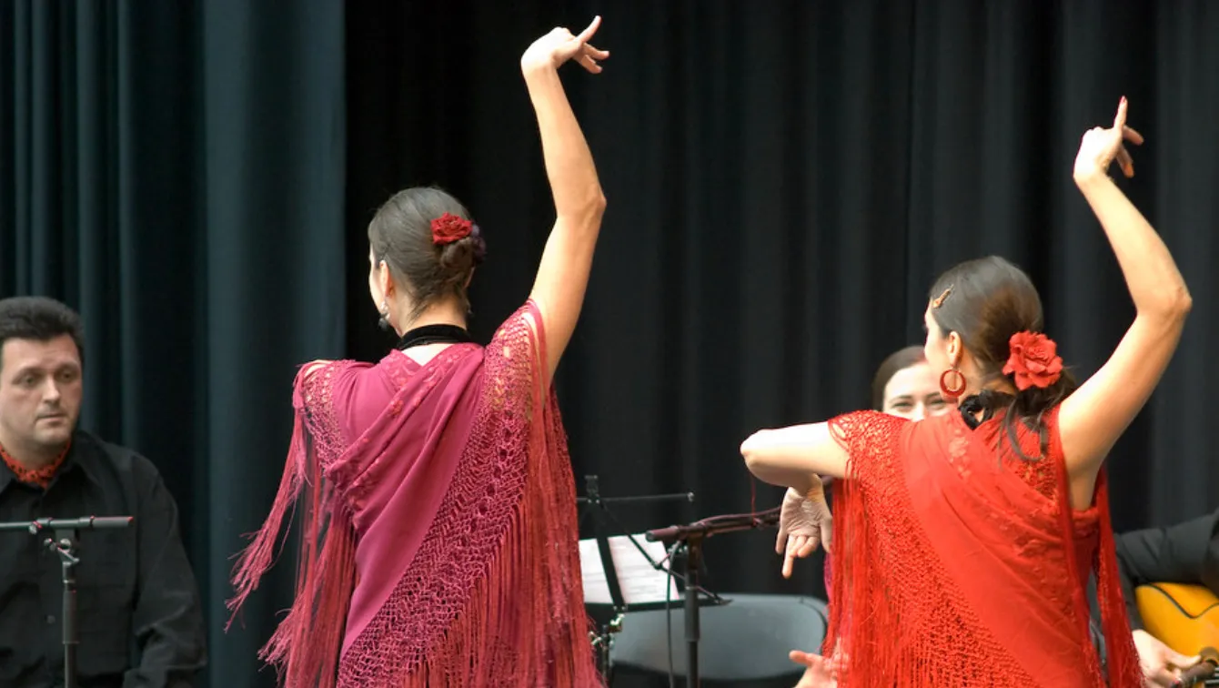 Two women in red shawls perform a dance with musicians in the background for a Europe general knowledge quiz.
