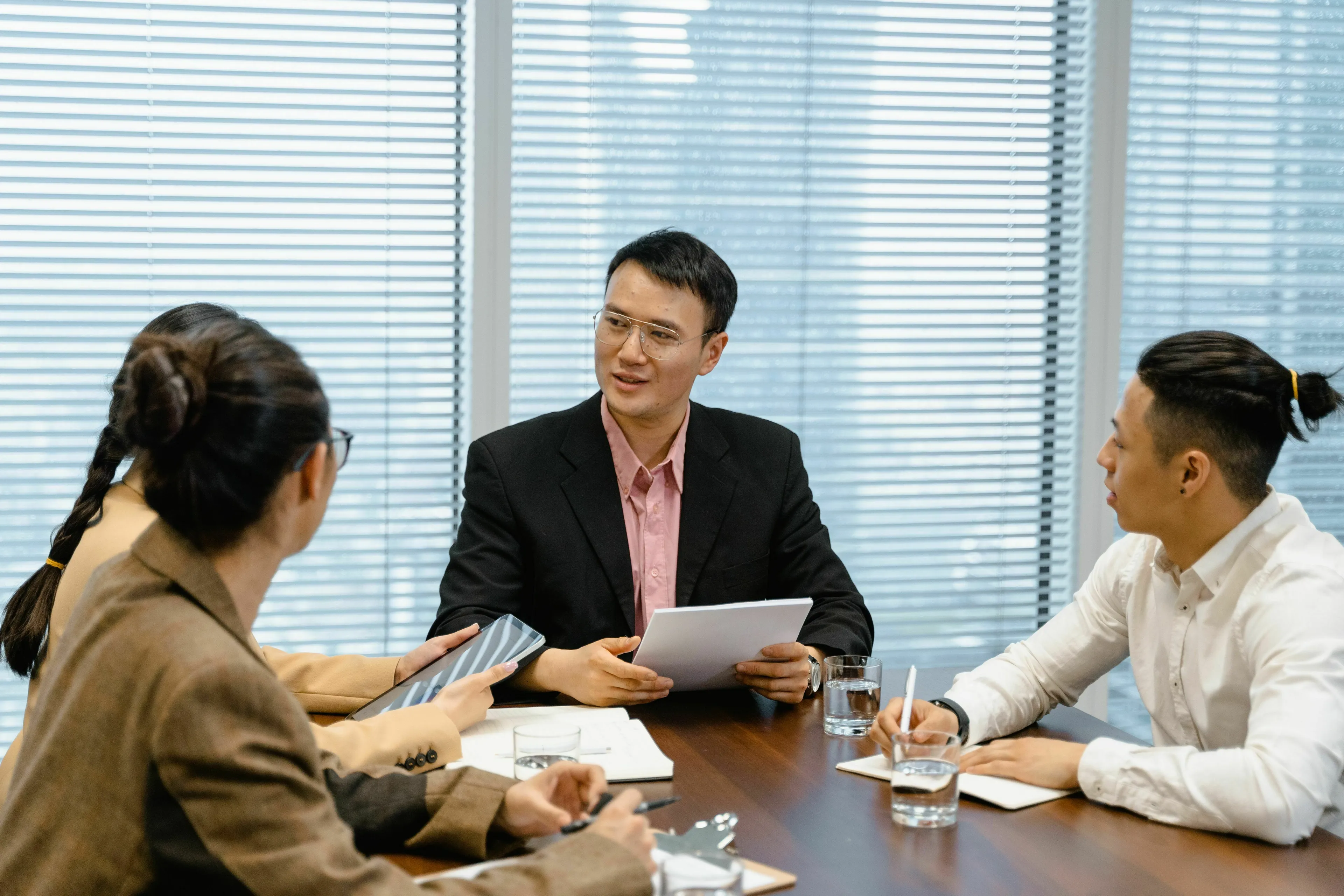 Three professionals in a meeting, one speaking while holding papers. How do you handle being wrong?