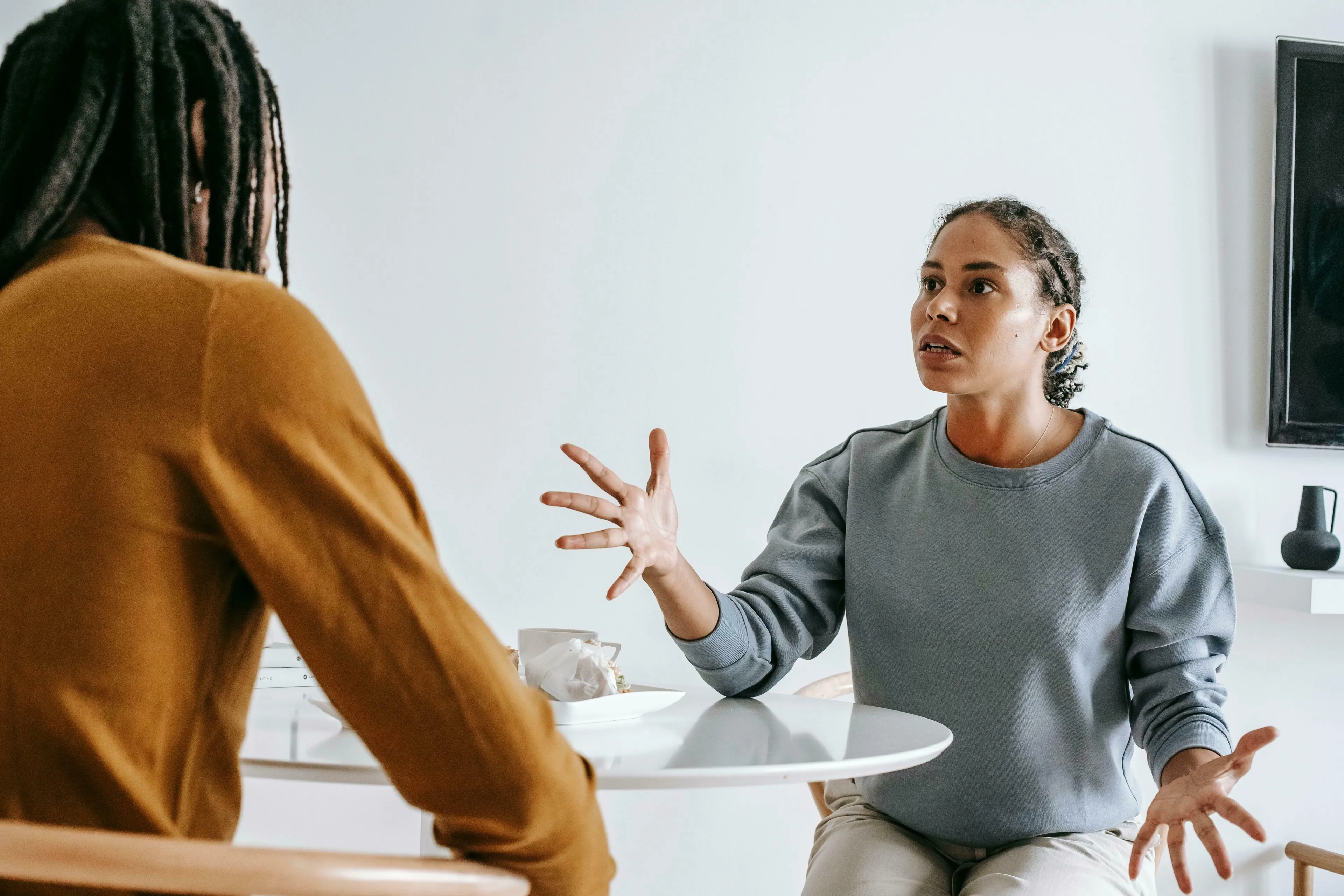 A woman explains to a person with dreadlocks how being wrong helps her to change her position quickly.