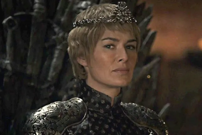 Cersei Lannister wearing a detailed crown and ornate, dark armor, looking directly at the viewer with a stern expression.