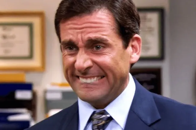 Michael Scott looking distressed and making a strained face, clenching his teeth and furrowing his brow.