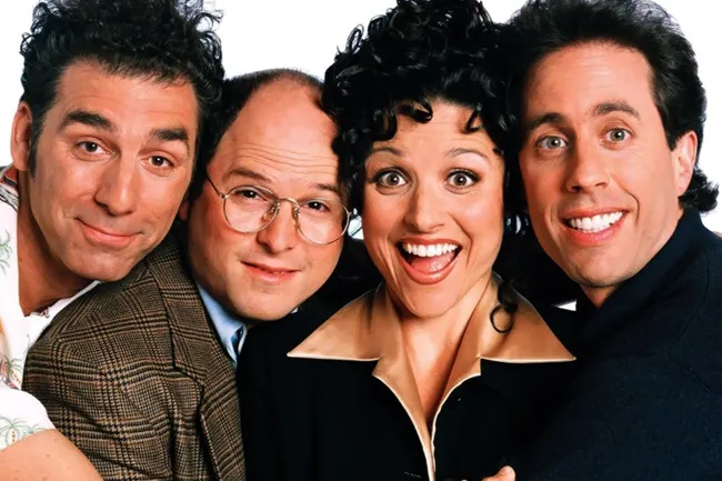 The four main cast members of Seinfeld smiling and posing closely together, showcasing the popular TV show.