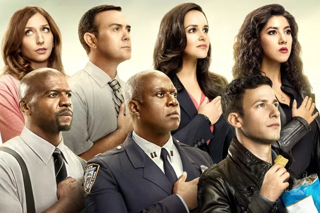 The cast of Brooklyn Nine-Nine standing with hands over their hearts, with Jake Peralta eating a chip. Pick a TV show.