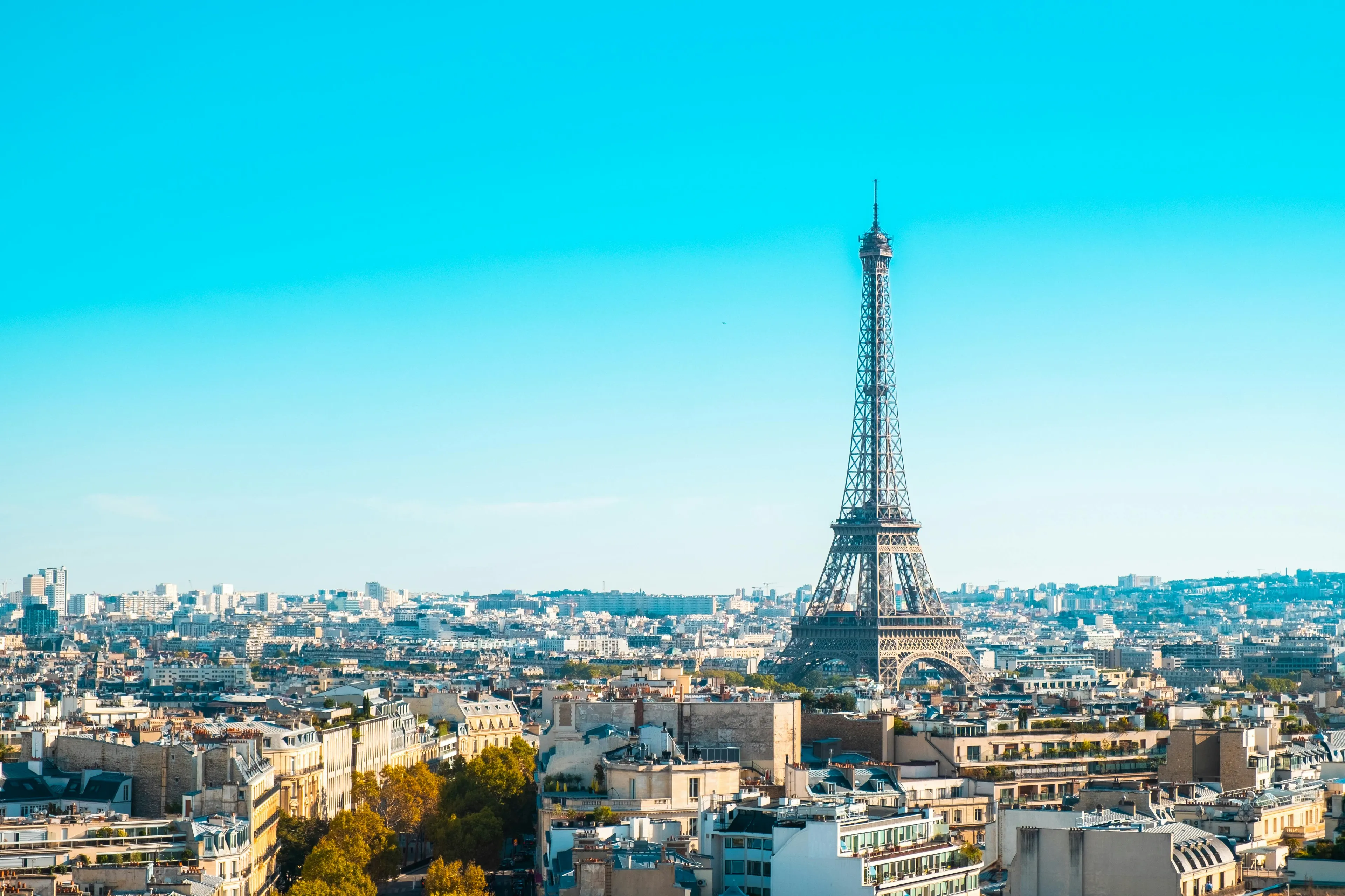 Eiffel Tower rises above the cityscape of Paris, France, under a clear blue sky, an ideal holiday destination.