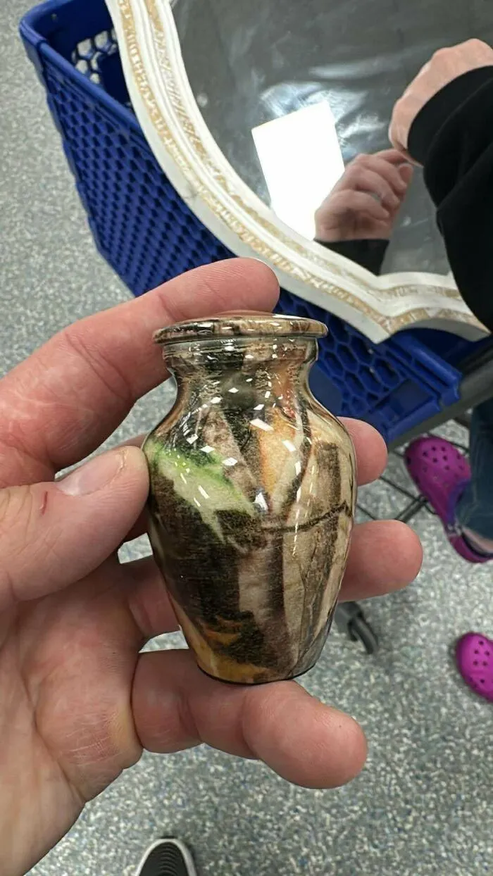 Small decorative urn with camouflage pattern held in hand at Goodwill