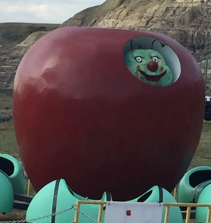 Creepy clown inside a large red apple statue outdoors