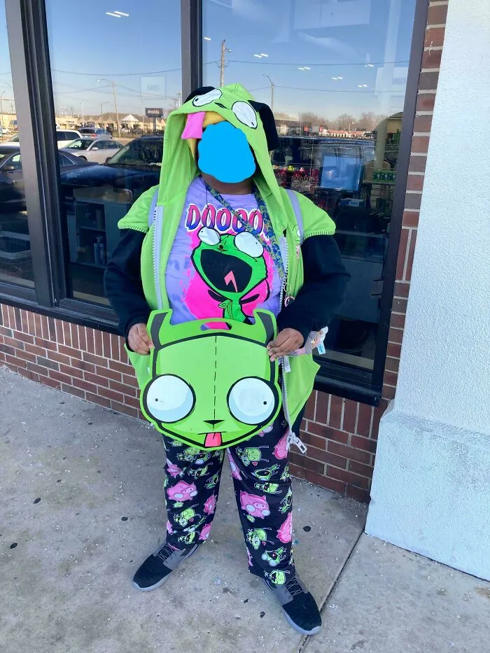 Person dressed in green cartoon-themed outfit holding matching handbag outside store