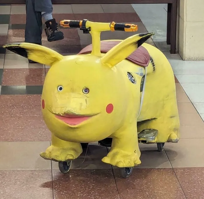 Worn-out yellow Pikachu scooter with visible damage and missing parts indoors
