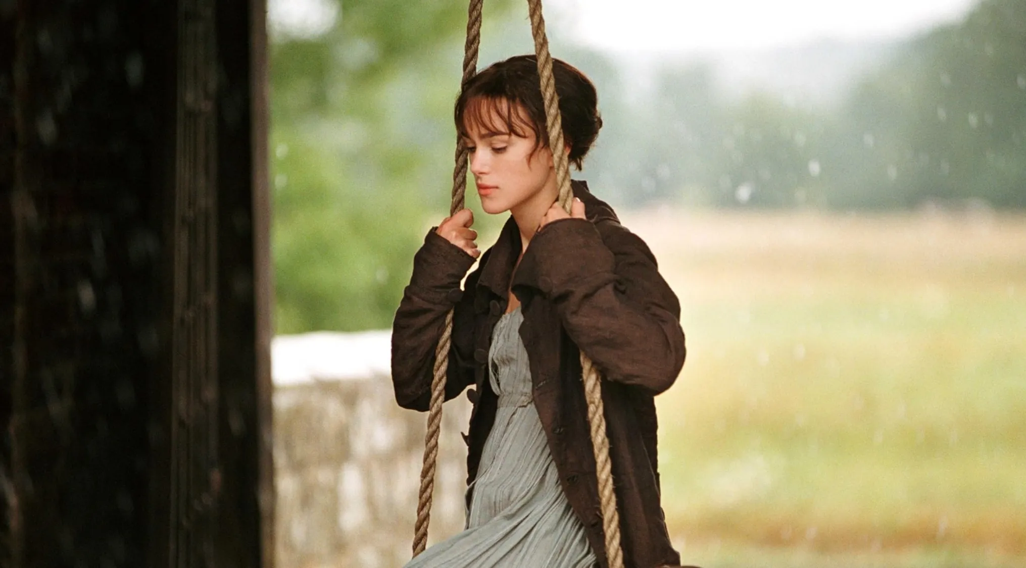 Elizabeth Bennet character on a swing, looking thoughtful, with rain falling in the background. Pub Quiz question.