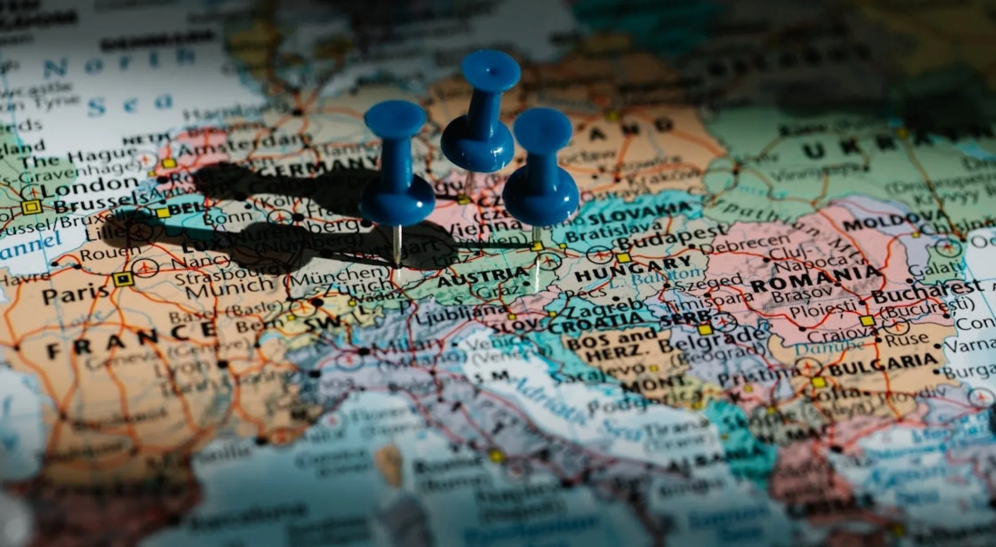 Three blue pushpins on a map of Europe, with shadows extending from them. Quiz on Marshall Plan in USA history.