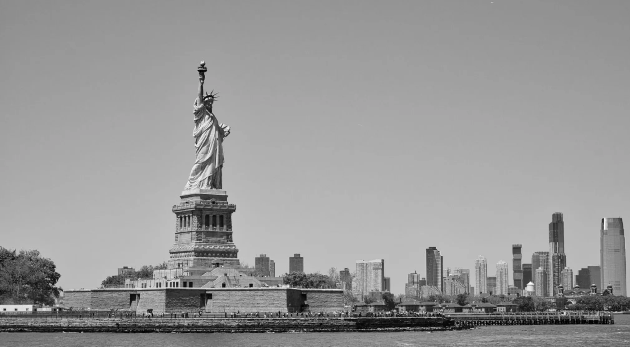 Black and white photo of the Statue of Liberty with New York City skyline in the background. USA Throughout History quiz.