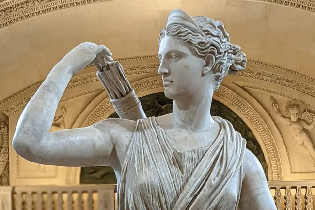 A white marble statue of Greek goddess Artemis with a quiver of arrows, looking right.