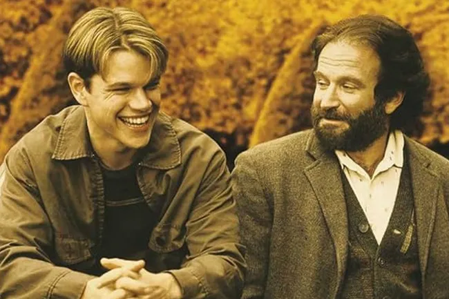 Matt Damon smiling, sitting next to Robin Williams who is looking at him. Good Will Hunting is a movie you could watch on repeat.