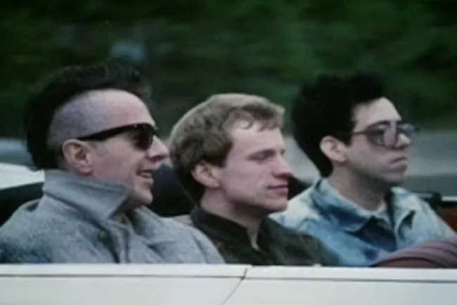Three men in a car, including one with a mohawk and sunglasses, evoking The Clash's Should I Stay or Should I Go.