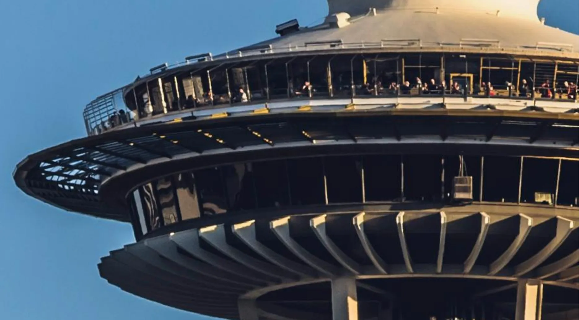 Guess the landmark from the zoomed-in image. A close-up of a distinct tower's observation deck against a blue sky.