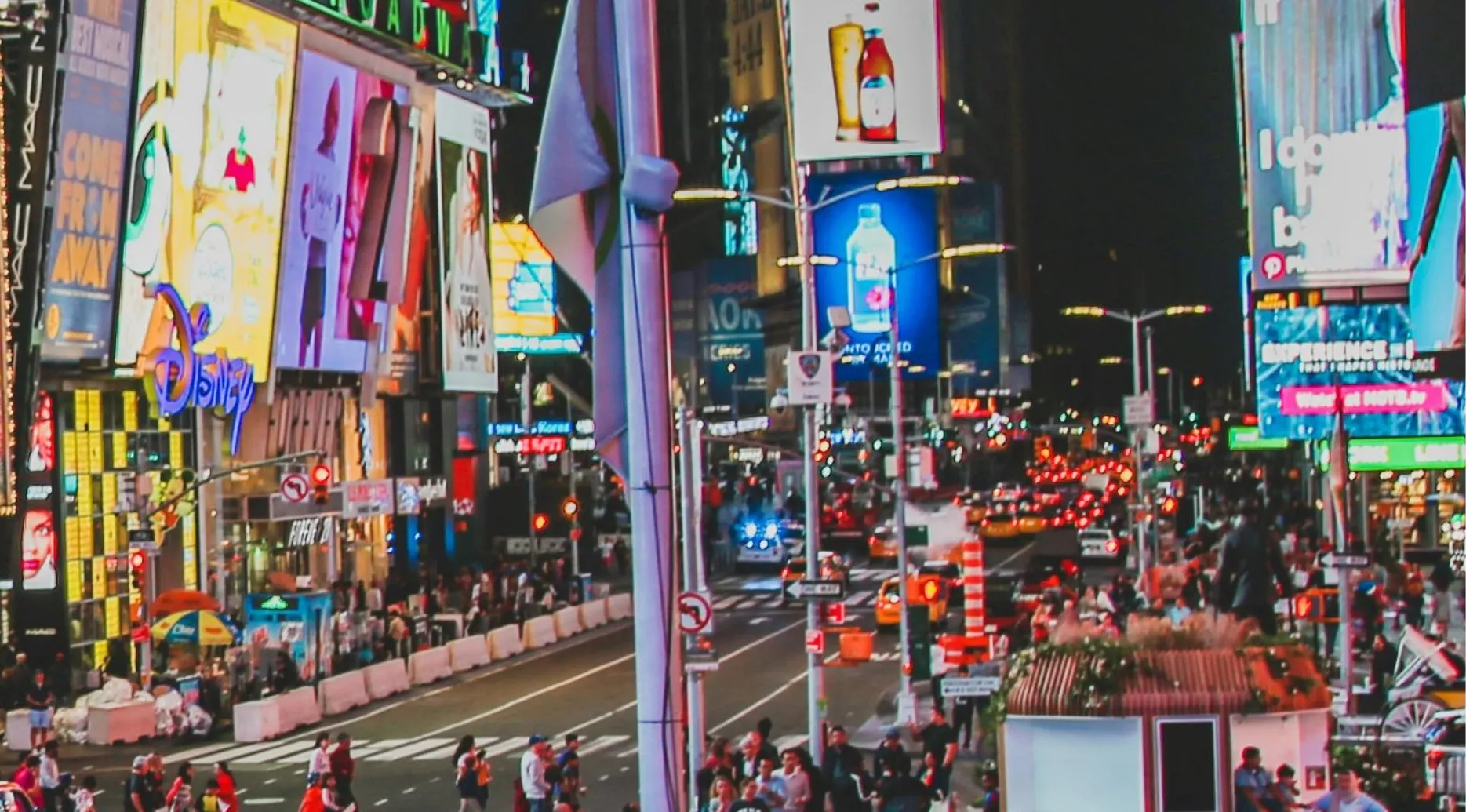 A zoomed-in photo of Times Square at night with bright billboards and heavy traffic. Guess the landmark.