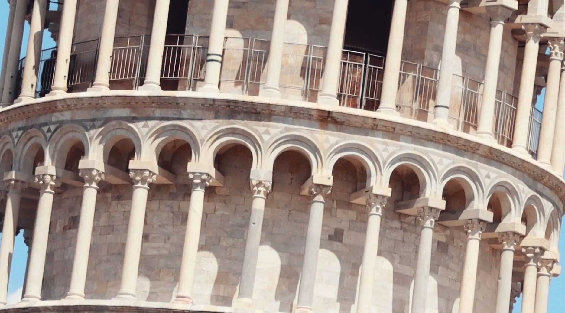 A zoomed-in photo of the Leaning Tower of Pisa, showing its iconic white marble arches and columns. Guess the landmark.