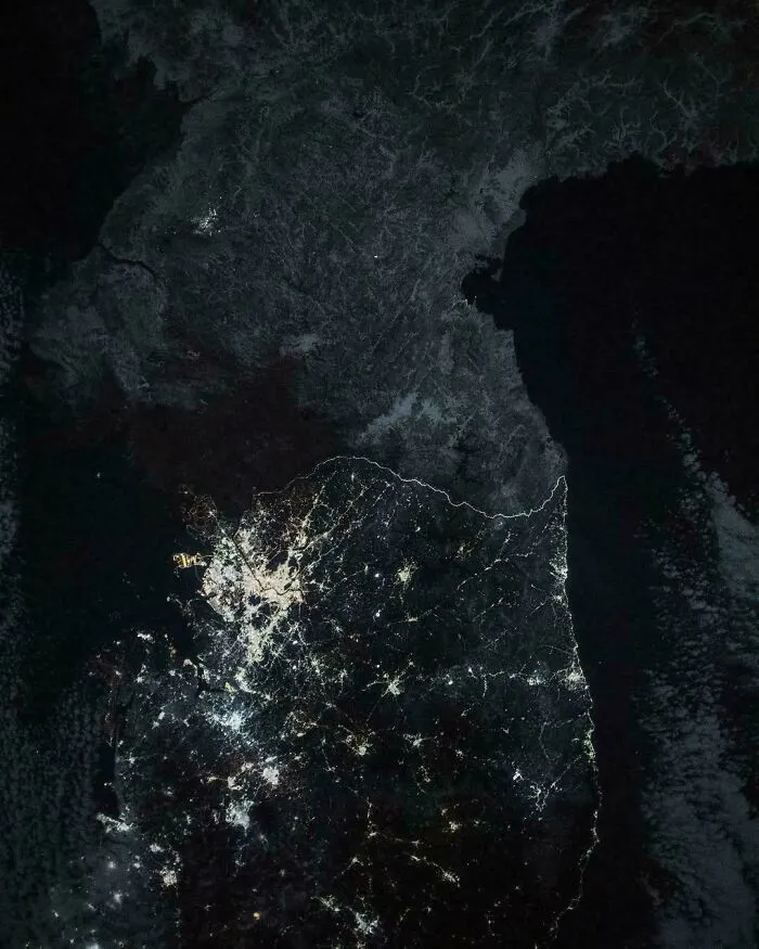 Satellite image showing South Korea lit up at night next to a dark North Korea