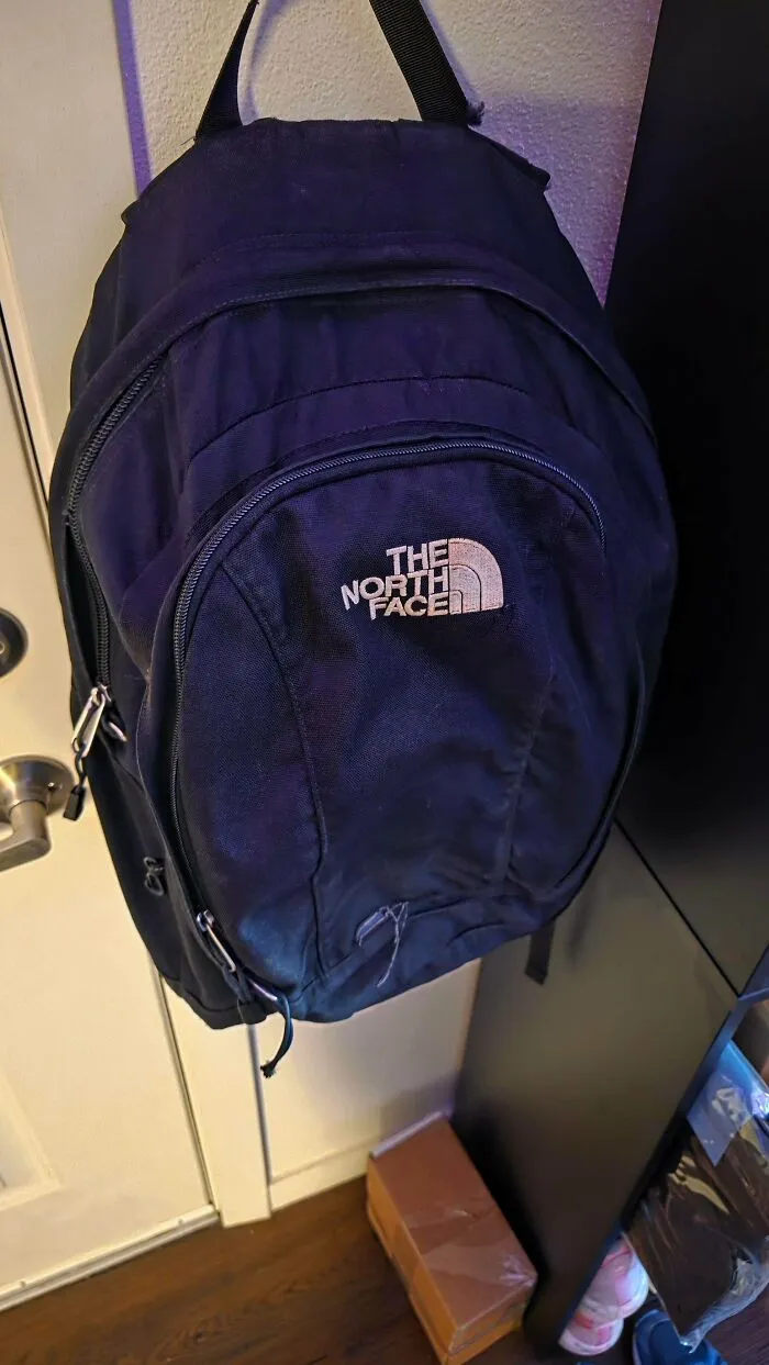 Black North Face backpack hanging on a door, an example of old products that refuse to give up.