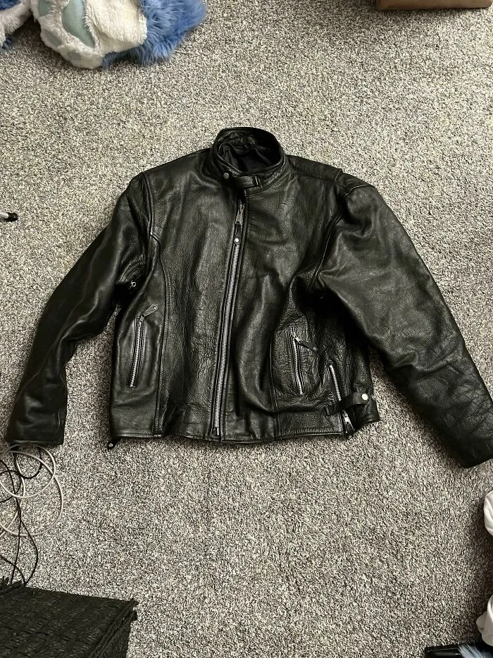 A durable black leather jacket laid flat, demonstrating old products built for long-term daily use.