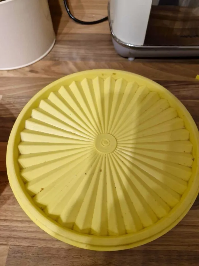 Classic yellow sunburst lid resting flat on a wooden countertop, exemplifying old products built for long term use.