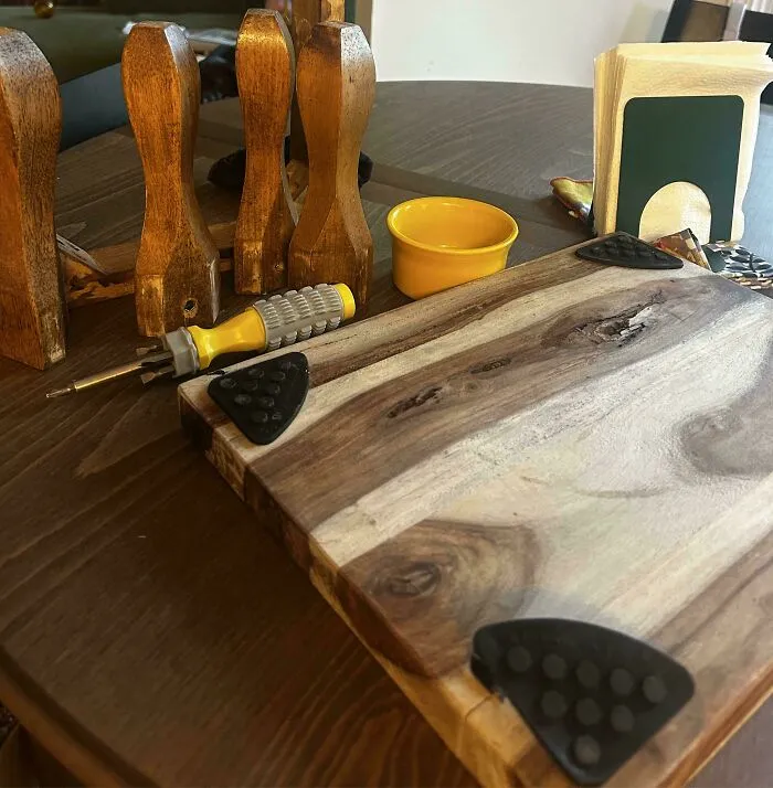 Wooden cutting board equipped with corner grips and a screwdriver nearby, reflecting old products with durable design.