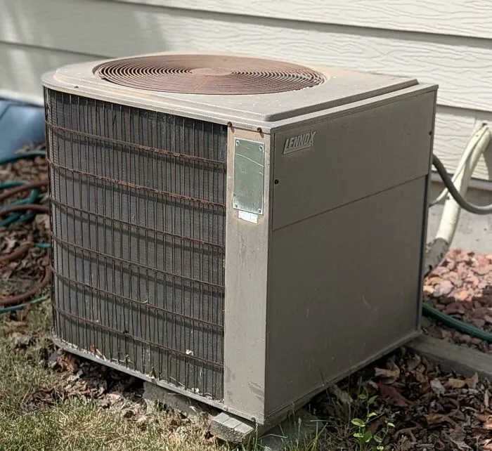 An old Lennox air conditioner unit installed outdoors, demonstrating old products that continue to function over time