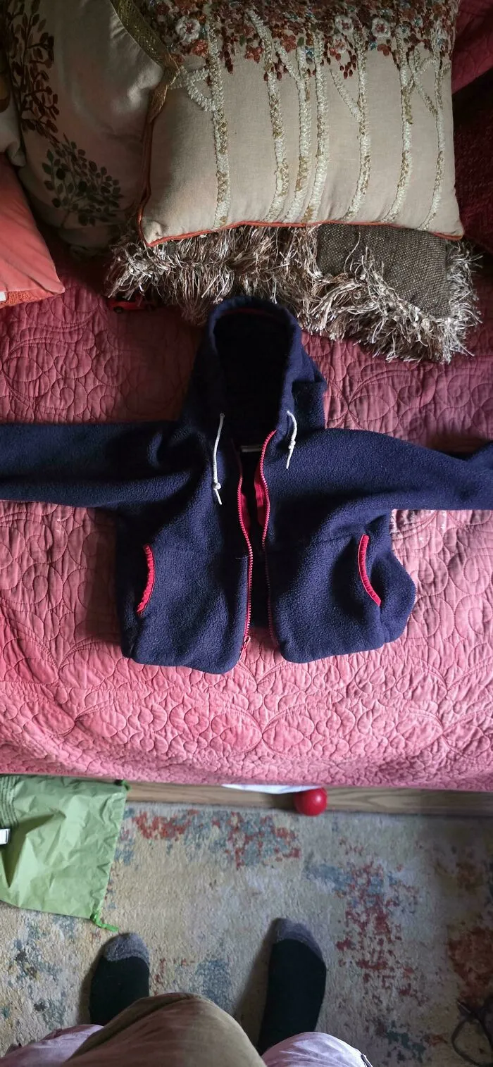 A well-worn navy fleece hoodie laid on a bed, showing old products that continue to last for years.