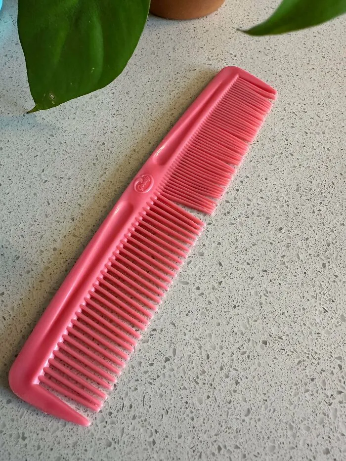 A classic pink Goody hair comb resting on a surface, highlighting old products that withstand daily wear.