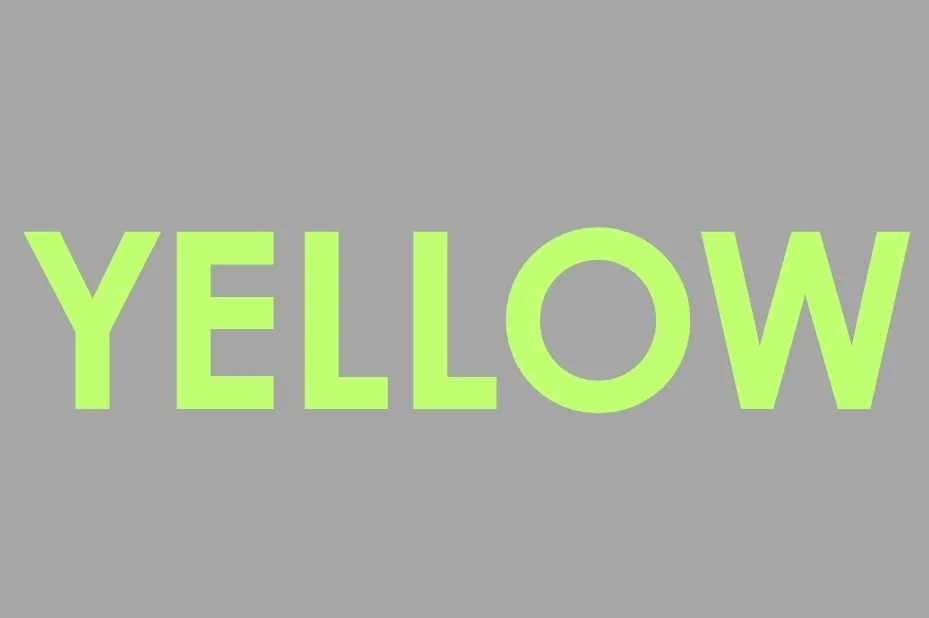 The word YELLOW in a vibrant green color, displayed prominently against a gray background, challenging color perception.