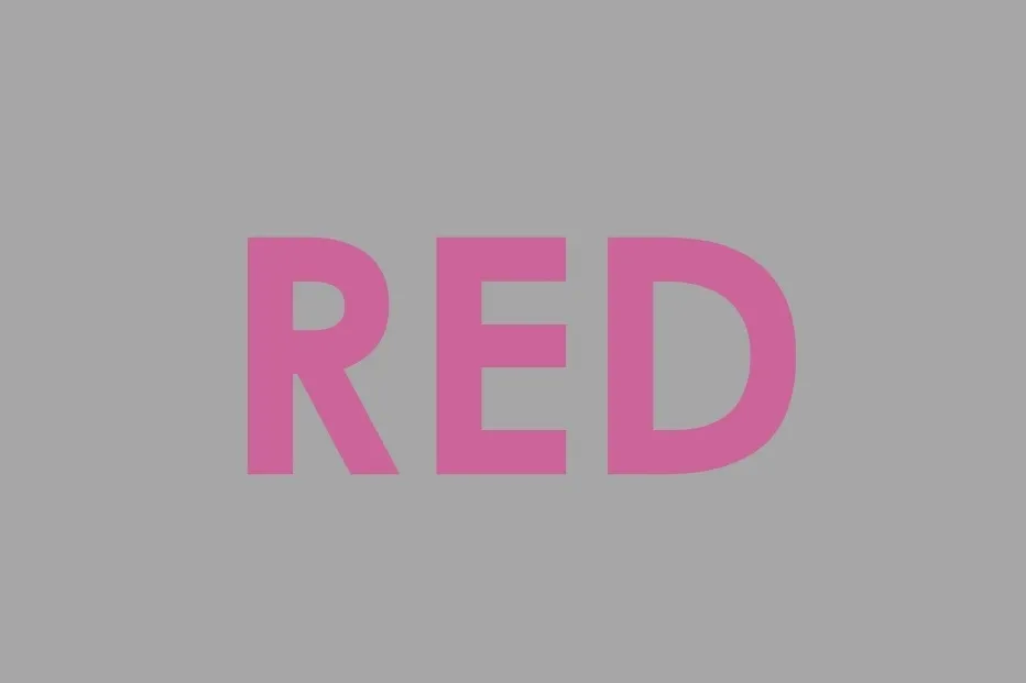 The word RED written in pink letters on a solid grey background, playing with perception of the color red.