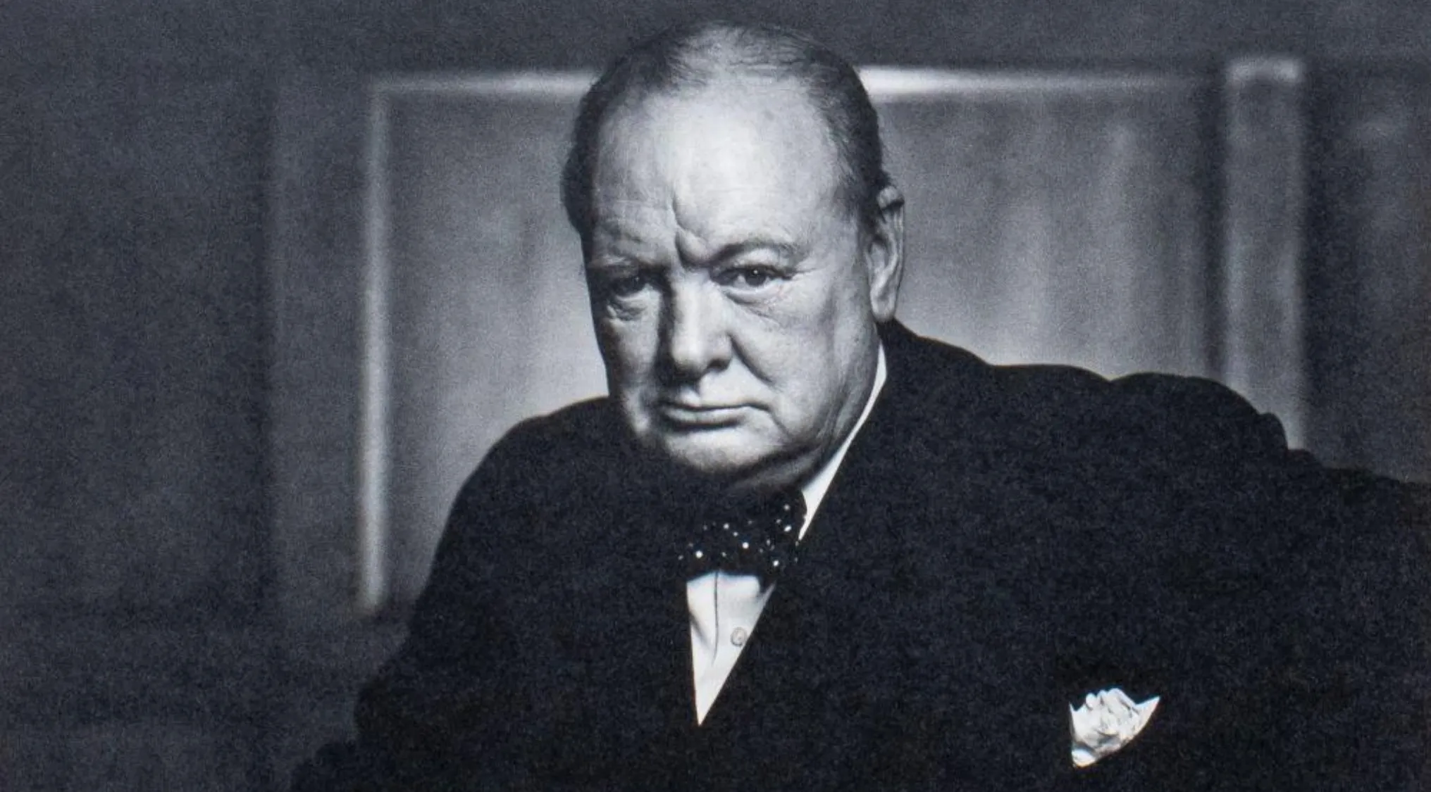 Black and white portrait of Winston Churchill in a suit and bow tie, his gaze serious. General Knowledge Quiz.