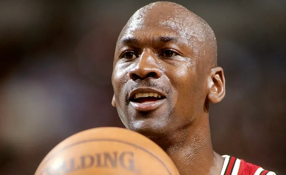 A close-up of Michael Jordan, sweaty and focused, holding a basketball during a game.