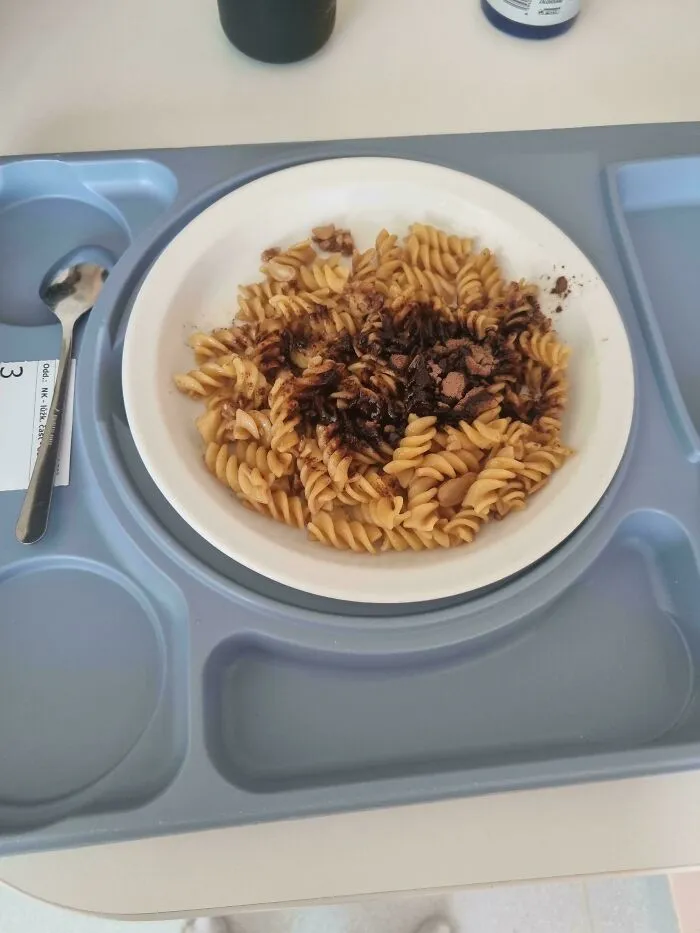 A plate of pasta topped with cocoa powder as a questionable food combo served on a hospital tray.