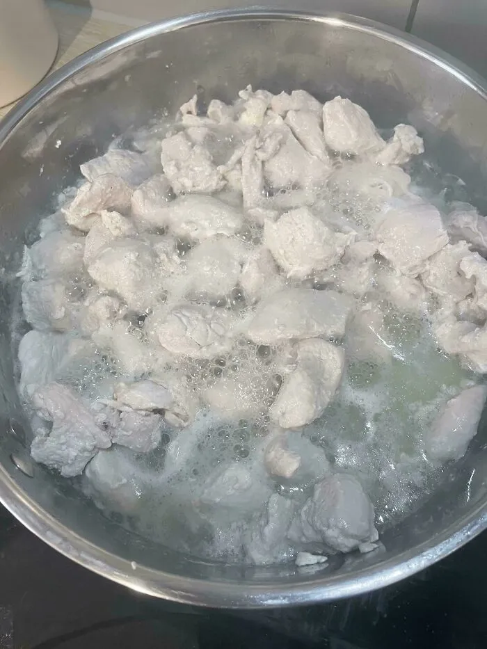 Chunks of plain chicken boiling in a pot, part of questionable food combos