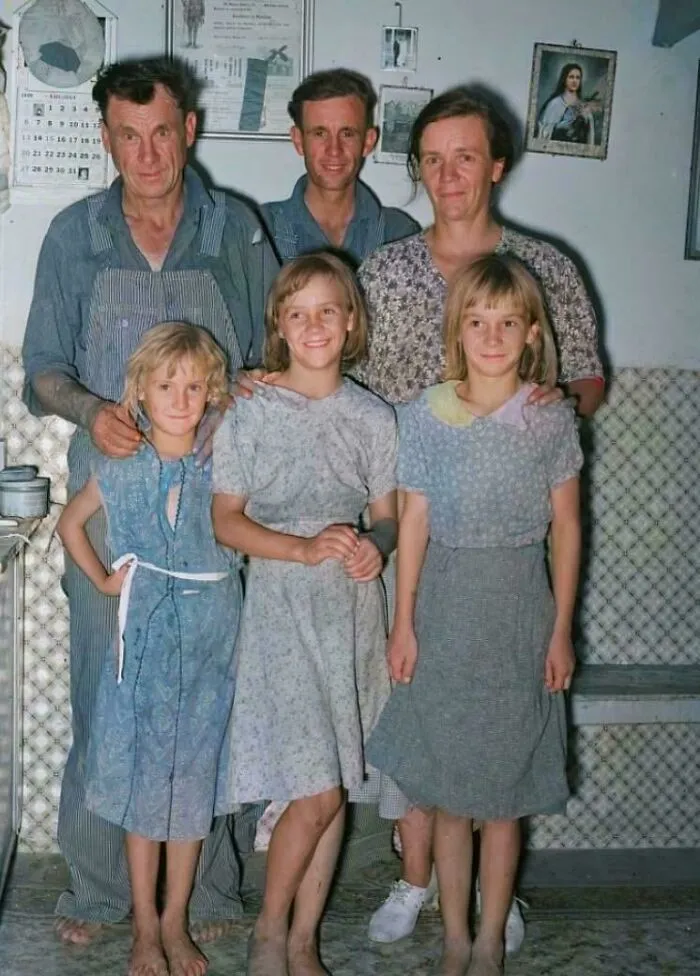 Una feliz familia campesina en su hogar en el condado de Sheridan, Kansas, 1939. Las tres niñas visten vestidos caseros de sacos de harina cosidos por su madre, reflejando la austeridad de la vida rural.