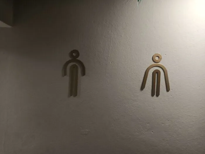 Awful design fail showing confusing restroom signs with unclear human figure shapes on wall