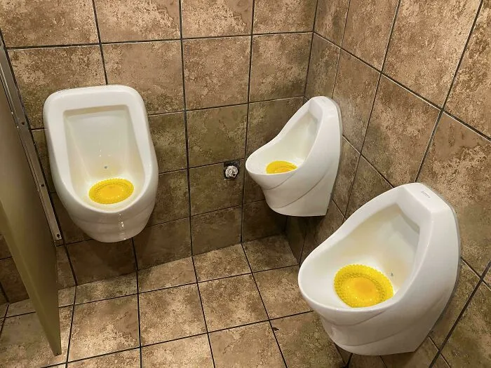 Three urinals in a bathroom corner with uncomfortable awkward placement