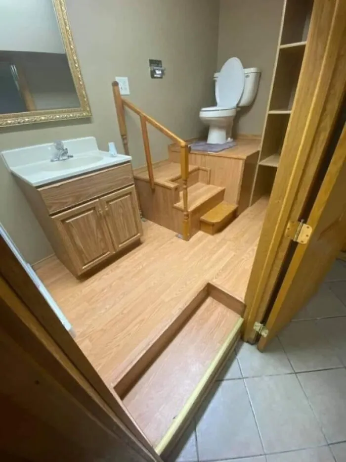 Bathroom with toilet elevated on wooden platform accessed by stairs design fail