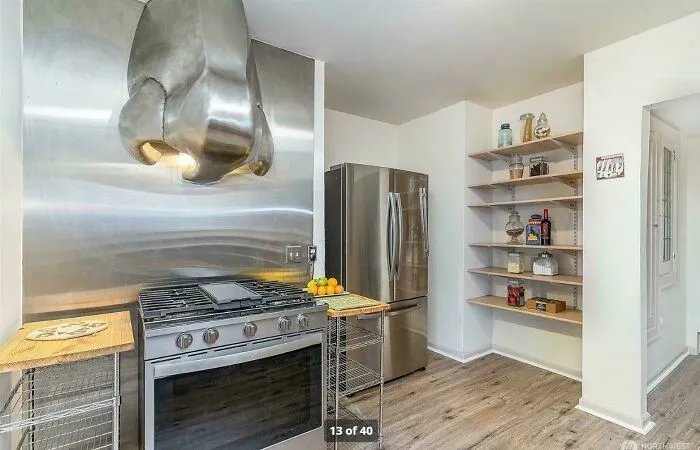 Kitchen with odd stainless steel stove hood and limited counter space design fail