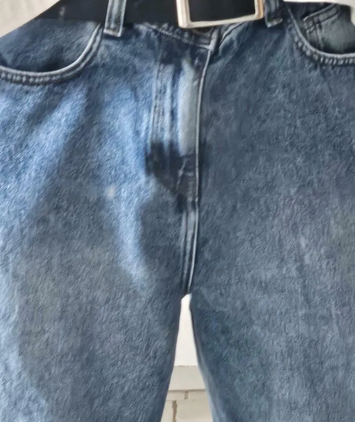 Close-up of blue jeans with an off-center zipper, exemplifying a bad clothing design.