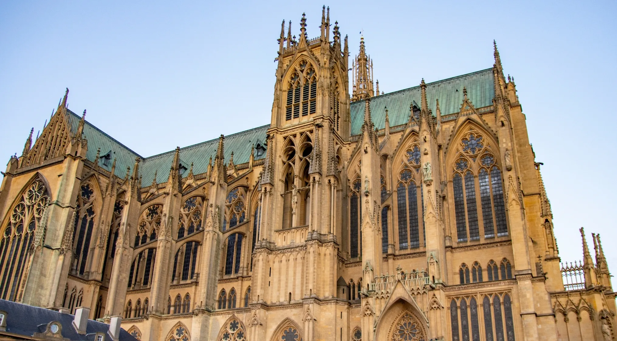 Magnificent Gothic architectural style cathedral with intricate details, pointed arches, and a teal roof under a clear sky.