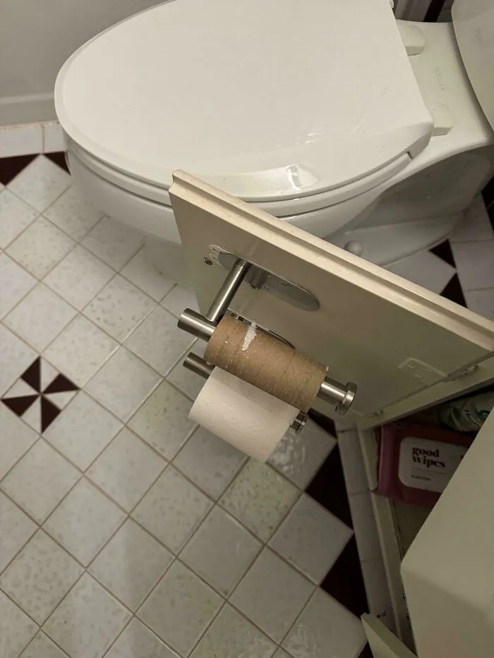 A roll of toilet paper mounted inside a cabinet door, a clever solution for a small bathroom.