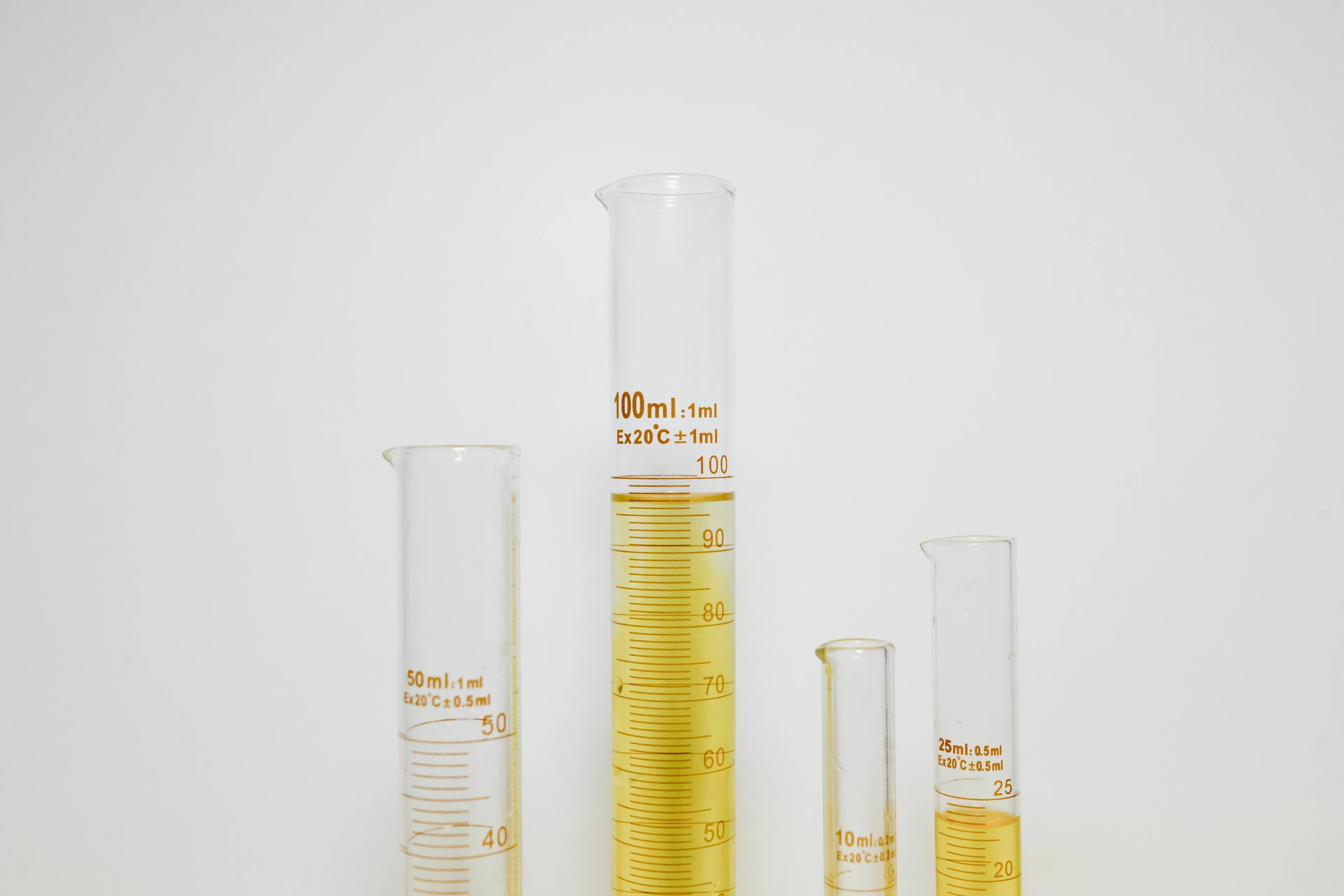 Science Human Biology Trivia: Graduated cylinders on a white background, one filled with dark yellow liquid representing darker urine during dehydration.