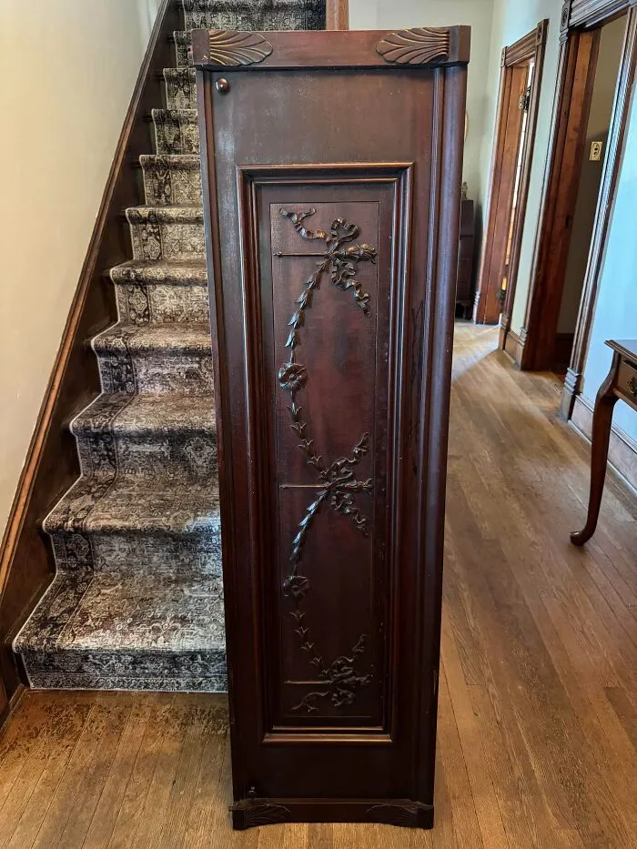 Tall dark wooden cabinet with carved floral detailing, an old treasure discovered by antique lovers