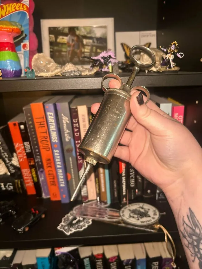 Hand holding an old metal syringe, one of many old treasures discovered by antique lovers