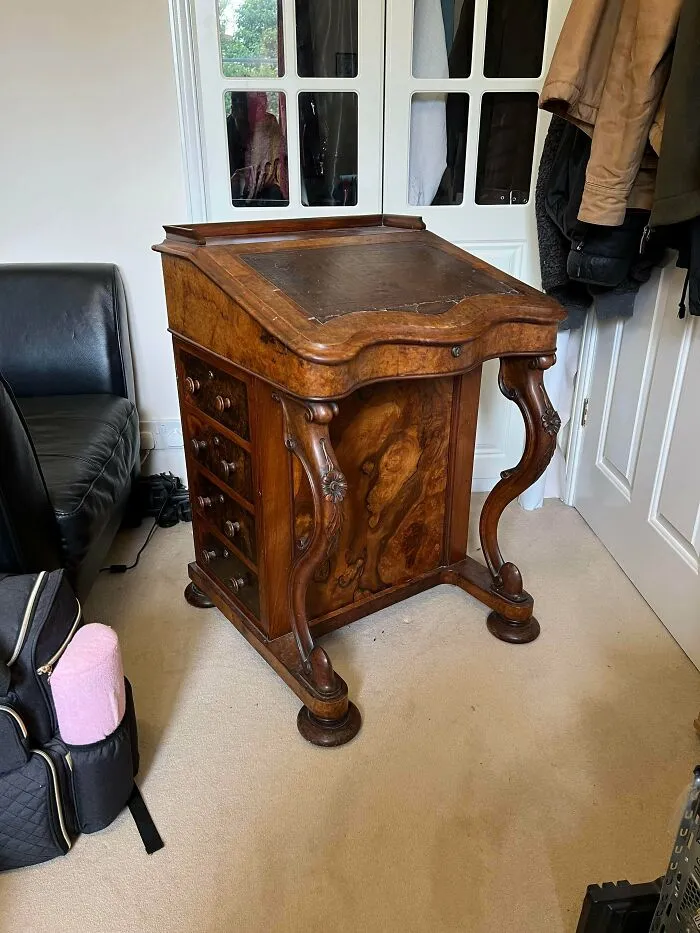 An ornate antique wooden slant-top writing desk with side drawers, a classic find for antique lovers.