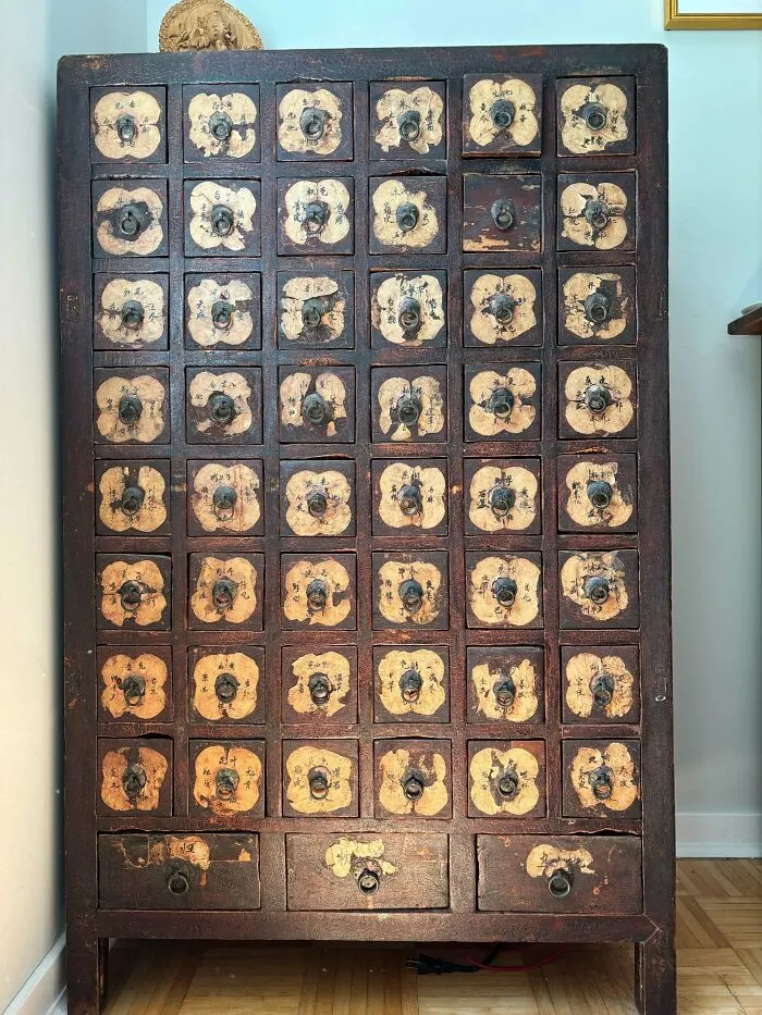 A tall vintage apothecary cabinet with many small drawers, perfect for antique lovers.