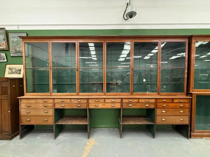 A massive antique wooden display cabinet with glass doors and multiple drawers